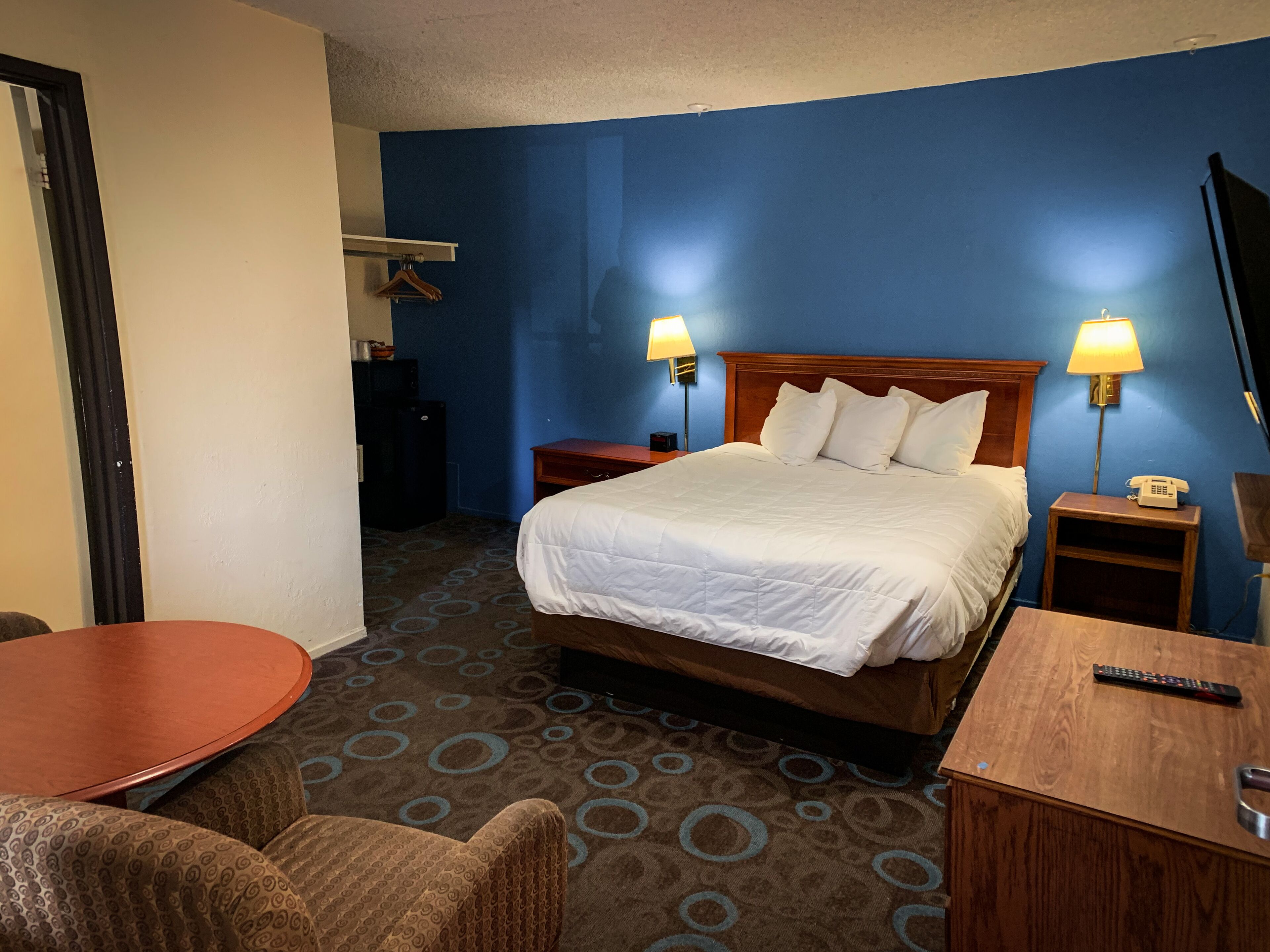 Ein Hotelzimmer mit einem Bett, zwei Nachttischlampen, einem Schreibtisch mit Telefon und einem Stuhl.