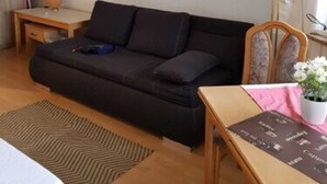 Una sala de estar acogedora con un sofá oscuro, una mesita de madera, un cuadro pequeño en la pared y una lámpara de pie.