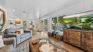 Uma sala de estar ampla, com uma televisão grande, armários de madeira e vista para uma paisagem.