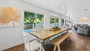 Um quarto amplo com uma mesa de jantar de madeira, cadeiras brancas e um banco.