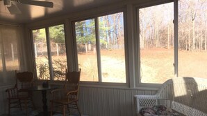 A sunroom with a table and chairs, large windows, and a wicker sofa.