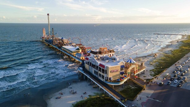 Un muelle se adentra en el océano, con un edificio que muestra un letrero que dice "Baja Grill".