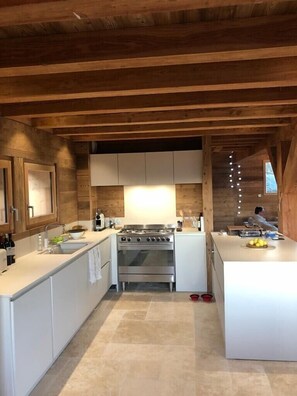 Een moderne keuken met witte kasten, een roestvrijstalen fornuis en een groot eiland met een fruitschaal.