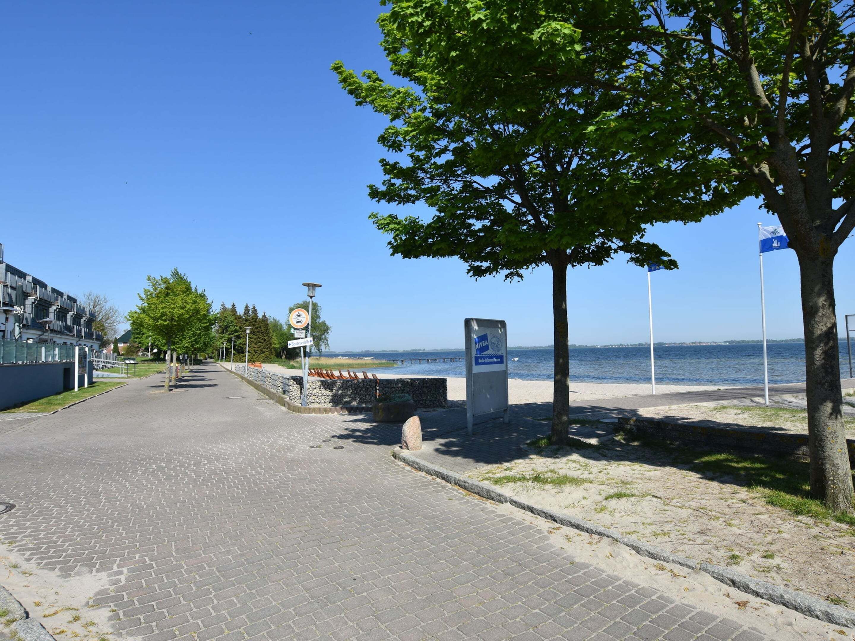 A paved pathway leading to a waterfront area with a sign indicating a no parking zone.