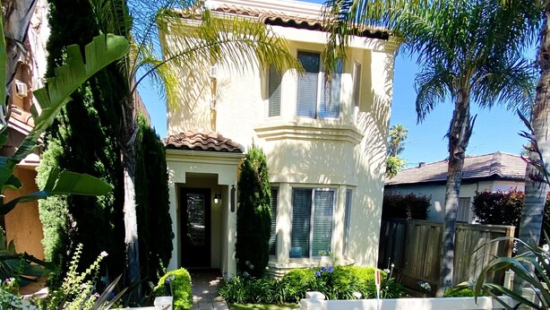 A two-story house with a front porch, a pathway leading to the door, and a white picket fence.