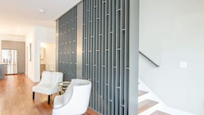 Ein modernes Interieur mit Holzboden, einem weißen Stuhl, einem kleinen runden Tisch und einer grauen Trennwand.