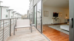 Eine moderne Wohnung mit Balkon, einem Wohnzimmer mit Sofa, Fernseher und Schrank.