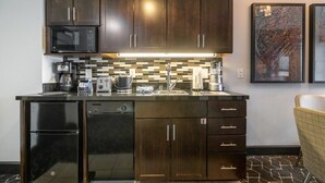 Una cocina moderna con armarios de madera oscura, un refrigerador negro, un microondas y un salpicadero de azulejos.