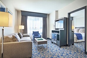 Habitación de hotel con sofá, una mesita, televisión y cama.