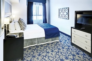 A hotel room with a bed, a TV, a dresser, and a patterned carpet. - San Francisco | City Stay | Fitness Center & Game Room | 3BR Sleeps 6 (San Francisco)