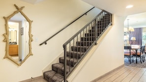 A staircase with a metal railing, carpeted steps, and a wooden-framed mirror on the wall. - Angels Camp | Friends & Family Golf Getaway | Pool + Golf | 3BR Sleeps 8 (Angels Camp)