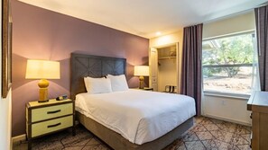 Una habitación de hotel con una cama, dos mesitas de noche con lámparas, un armario y una ventana con cortinas.