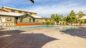 A swimming pool area with lounge chairs and a building with a glass facade.