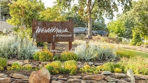 Un letrero de 'Wynham' con diseño rústico, rodeado de un jardín paisajístico con diversas plantas y flores.