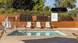 Un área de piscina con una pileta rectangular, sillas de descanso y un cerramiento.