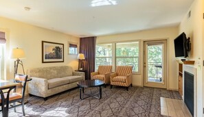A living room with a sofa, two armchairs, a coffee table, a fireplace, and a TV. - Angels Camp | Friends & Family Golf Getaway | Pool + Golf | 3BR Sleeps 8 (Angels Camp)