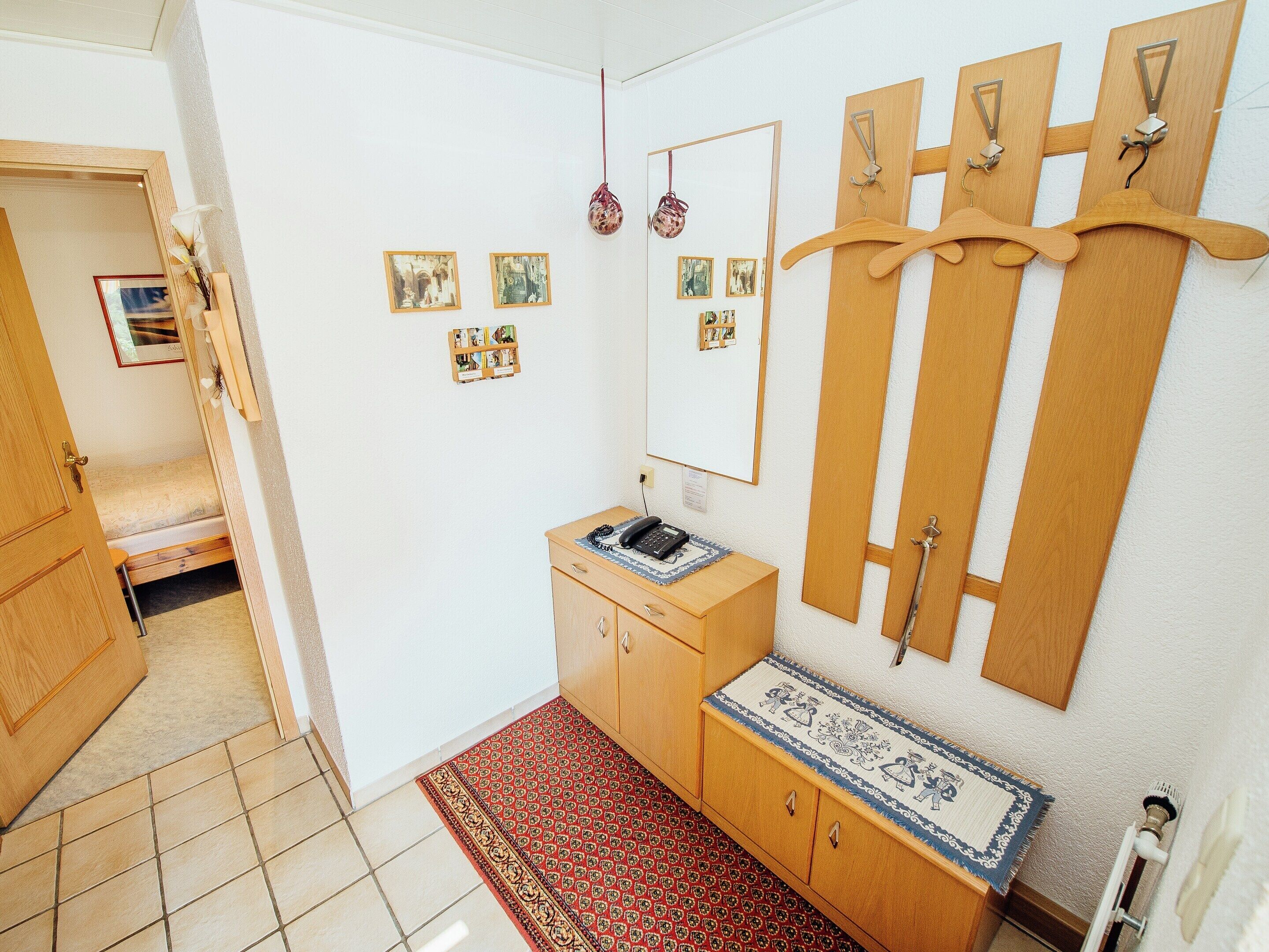 A small, clean room with a wooden cabinet, a mirror, and a red patterned rug.
