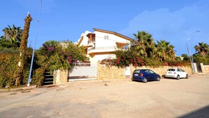 A two-story house with a balcony, surrounded by lush greenery and palm trees. - Lush Holiday Home in Sciacca near Golf Course (Sciacca)