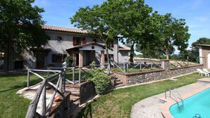 A villa with a swimming pool, stone walls, and a wooden fence.