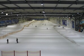 Eine Indoor-Skipiste mit mehreren Pisten und einer Sicherheitsnetz-Absicherung.