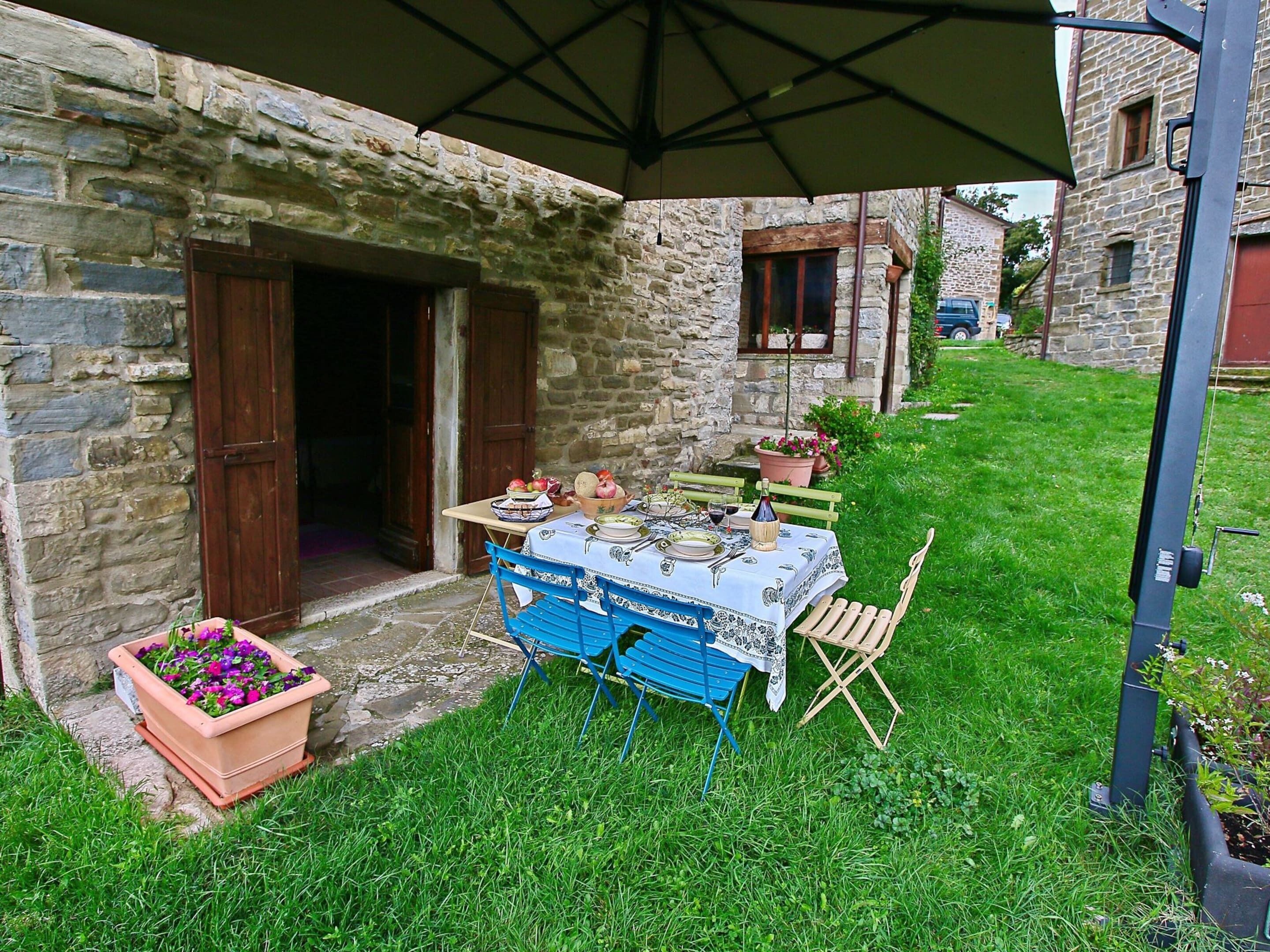 A stone building with a table set for dining, a chair, and a potted plant.