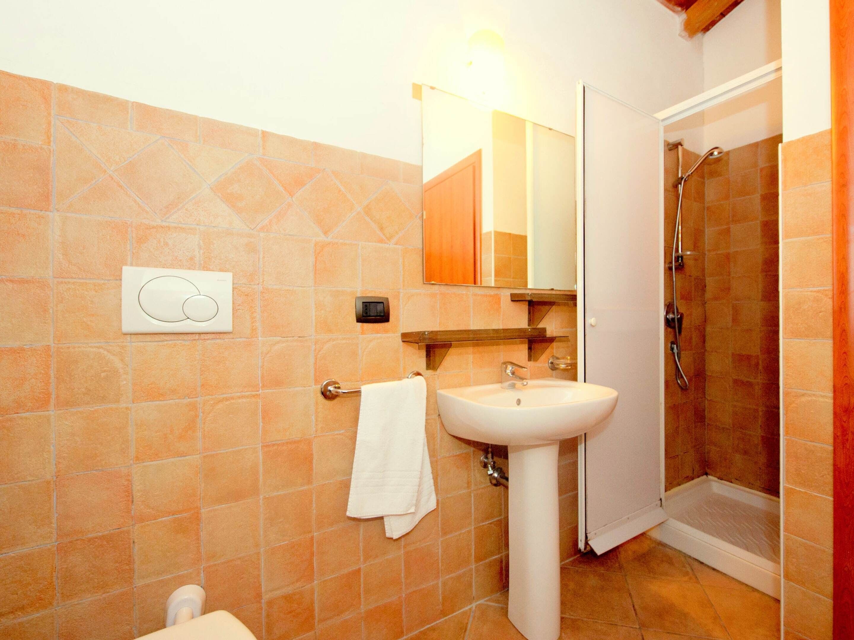 A bathroom with a white sink, a mirror, a towel rack, and a shower area.