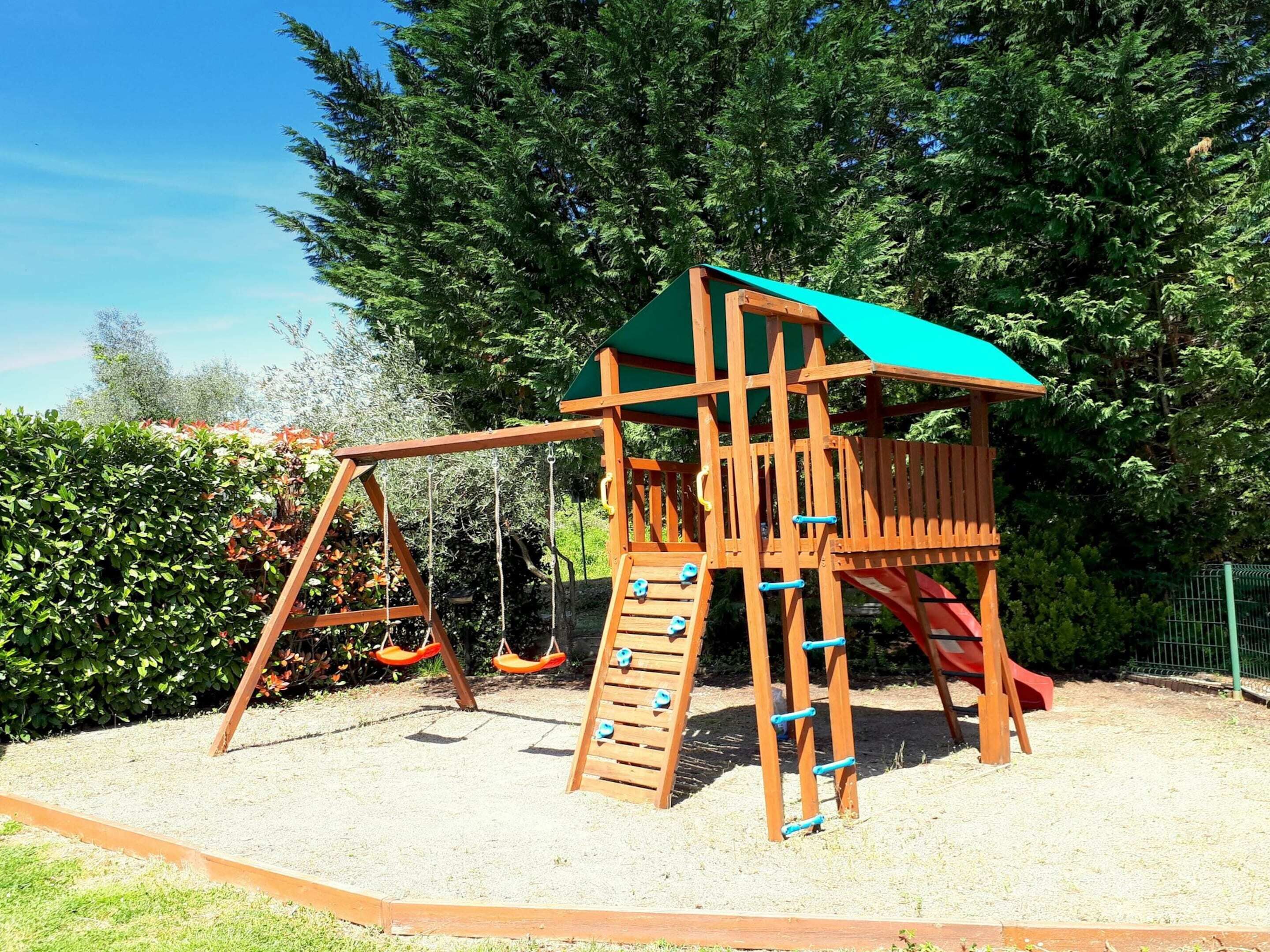 Estructura de juegos de madera con tobogán, columpios y elementos para escalar.