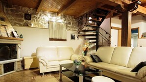 Un salon chaleureux avec un mur en pierre, une cheminée, un canapé, une table basse et un escalier.