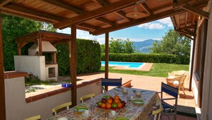 Une terrasse extérieure dotée d’un espace repas couvert, d’une piscine et offrant une vue sur les montagnes.