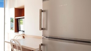 A stainless steel Kendo refrigerator in a kitchen with a wooden table and chairs. - Modern Apartment in Rimini With Balcony (Rimini)