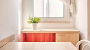 A room with a wooden desk, a white chair, a window with white curtains, and a potted plant on the desk. - Modern Apartment in Rimini With Balcony (Rimini)