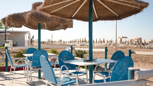 A beachside café with outdoor seating, including tables and chairs, and thatched umbrellas providing shade. - Modern Apartment in Rimini With Balcony (Rimini)