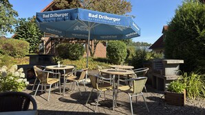 An outdoor seating area with tables and chairs under a blue umbrella with the text 'Bad Driburger.' - Holiday Home in the Teutoburg Forest (Brakel)