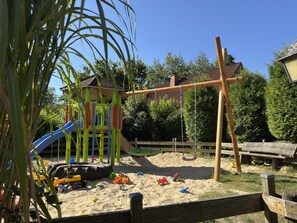 A playground with a slide, swings, and sand. - Holiday Home in the Teutoburg Forest (Brakel)