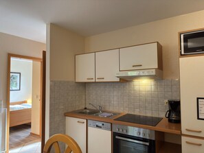 A compact kitchen with a dishwasher, oven, and a microwave. - Holiday Apartment in the Naturpur Holiday Village (Brakel)