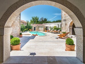 An outdoor swimming pool area with stone walls, lounge chairs, and potted plants. - Holiday Home with Swimming Pool near Lim Bay & Beach (Vrsar)
