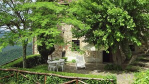 A rustic stone building with a small patio area, surrounded by lush greenery and trees. - Farmhouse in Dicomano With Tuscan Views (Dicomano)