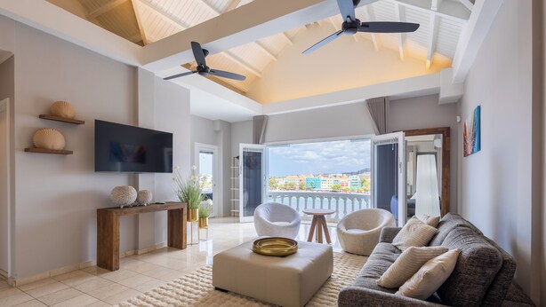 Ein modernes Wohnzimmer mit Flachbildfernseher, einer Couch, einem Couchtisch und einem Balkon mit Blick.