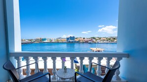 Ein Balkon mit Blick auf einen Hafen, ein Tisch mit einer Blume und zwei Stühle.