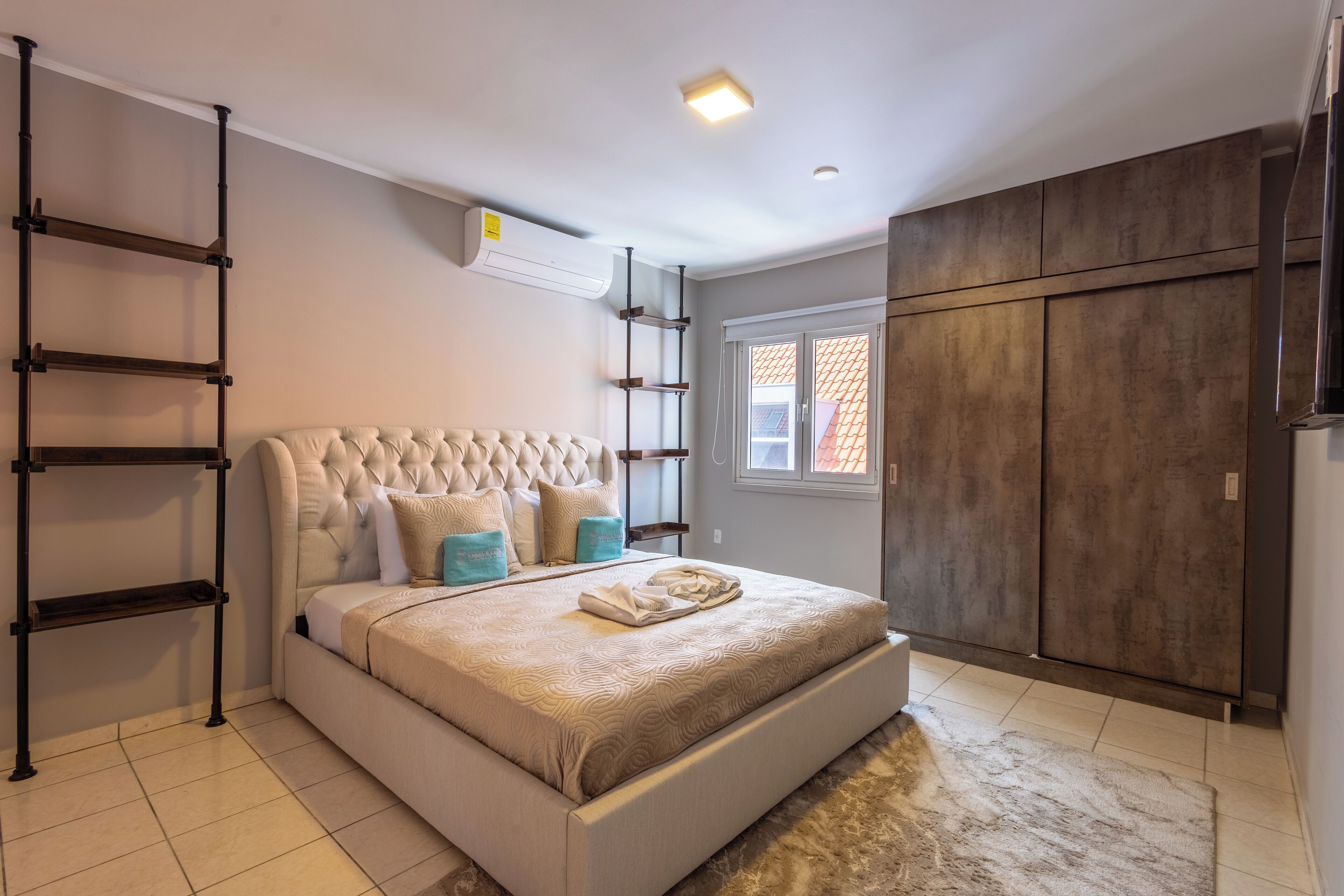 A bedroom with a large bed, a wardrobe, and a built-in shelf unit.