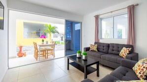 A modern living room with a sofa, coffee table, and a dining area with chairs and a table. - Luxury 2BR Apartment With Pool - Great Location (Willemstad)