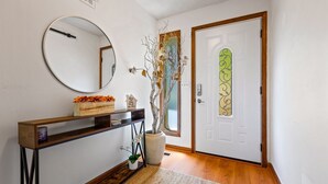 A hallway with a wooden console table, a mirror, a potted plant, and a door with a decorative glass panel. - Ultimate Stone Mountain I Cabin-Style I  Sleep 20 (Stone Mountain)