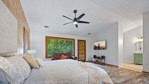 A bedroom with a large bed, a ceiling fan, a window with blinds, a desk with a chair, and a green cabinet. - Ultimate Stone Mountain I Cabin-Style I  Sleep 20 (Stone Mountain)