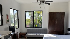 Un dormitorio moderno con cama, sofá, televisor, armario y ventilador de techo.