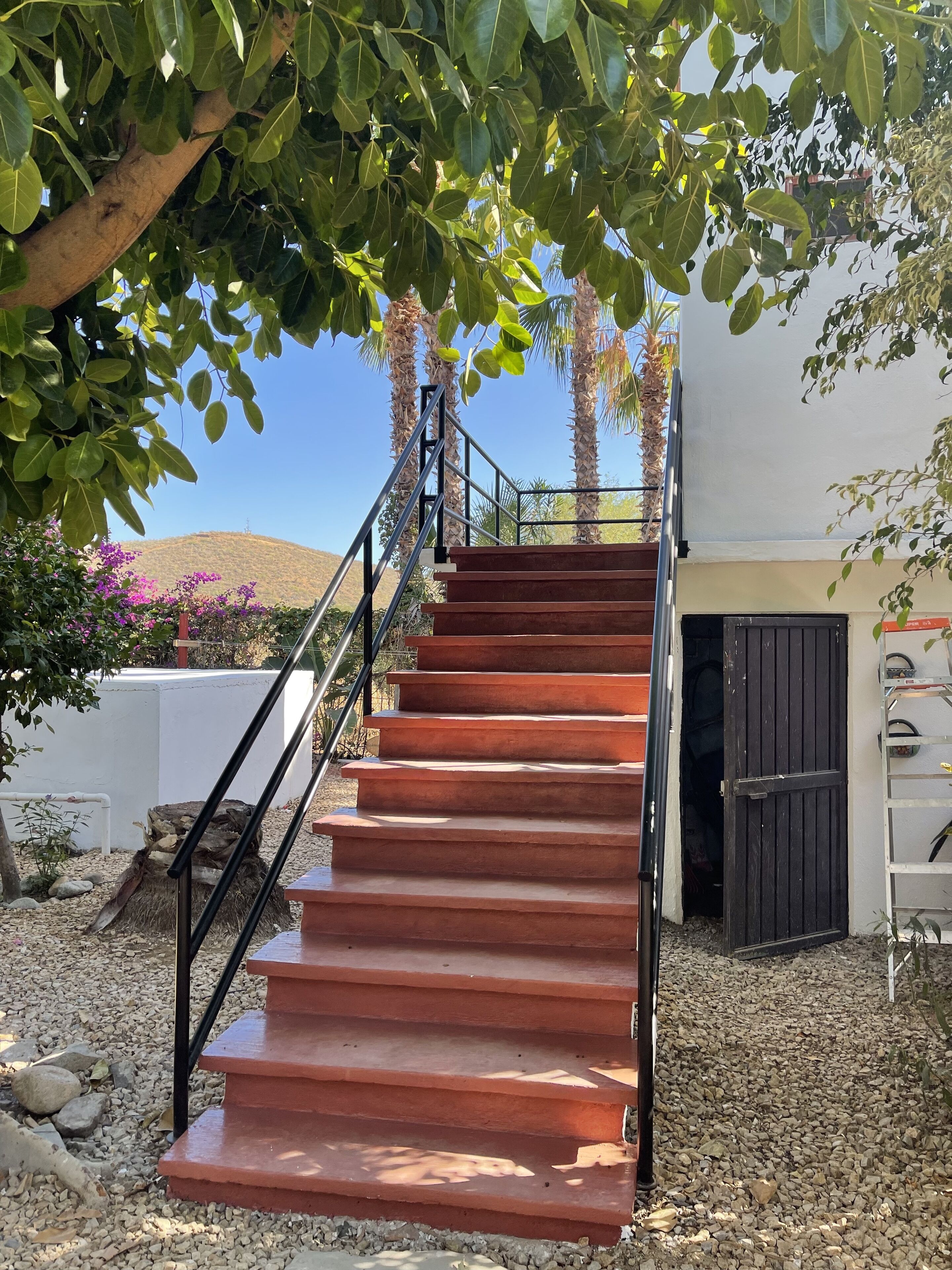 A staircase leading to a building with a white exterior and a black door.