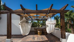Un espacio de estar al aire libre techado con dos hamacas, una mesa y sillas.
