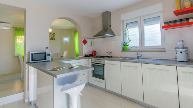 Una cocina moderna con una isla central, microondas, estufa y pileta.