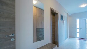 Un pasillo moderno con un banco de madera, un armario empotrado y una puerta que da a otra habitación.