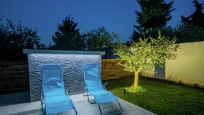Un patio con dos sillones de descanso y una pared de piedra.