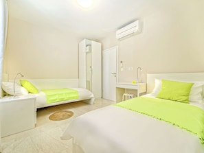 Two single beds with white bedding and green accents, accompanied by bedside tables and lamps, offer a comfortable retreat.